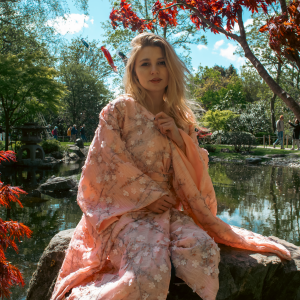 Justyna Sekmistrz posing in a garden of blooming tulips at Holland Park, wearing a soft pink kimono under midday sunlight.