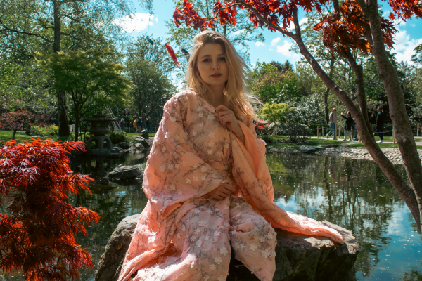 Justyna Sekmistrz posing in a garden of blooming tulips at Holland Park, wearing a soft pink kimono under midday sunlight.